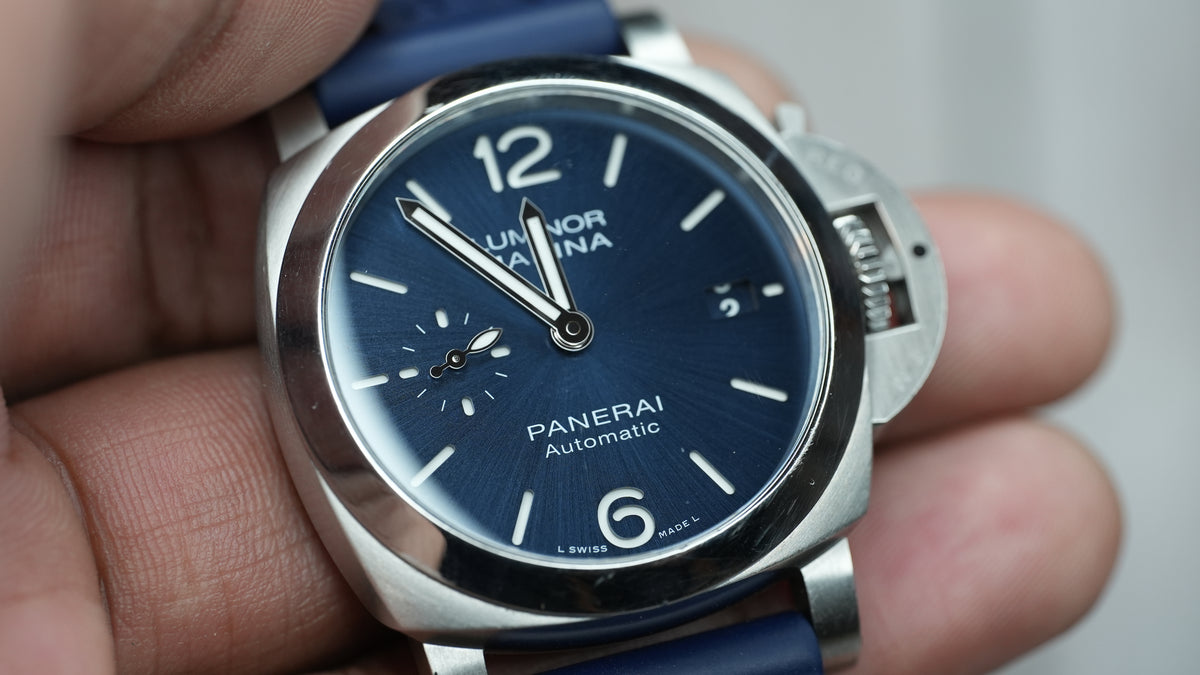 Panerai Luminor Marina PAM01370 held in hand, angled close-up of the blue dial, hands and date window.