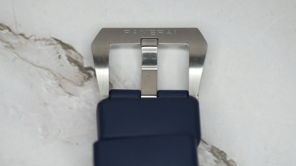 Panerai-signed stainless steel pin buckle on the blue rubber strap, close-up showing surface wear.
