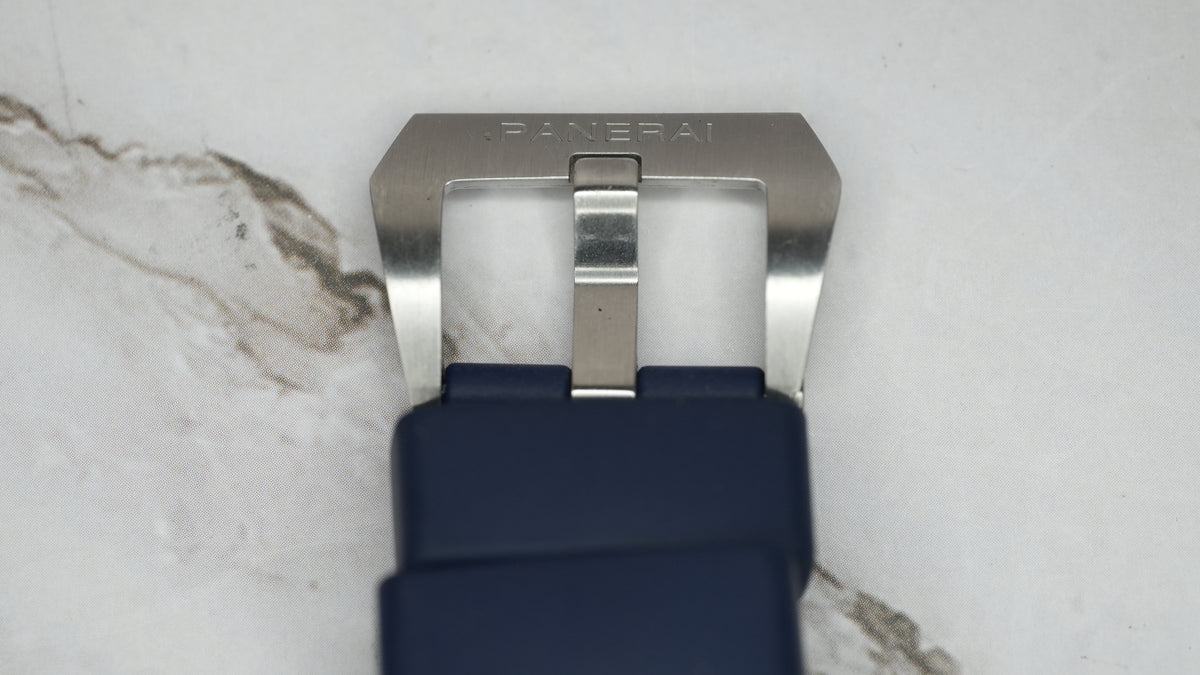 Panerai-signed stainless steel pin buckle on the blue rubber strap, close-up showing surface wear.
