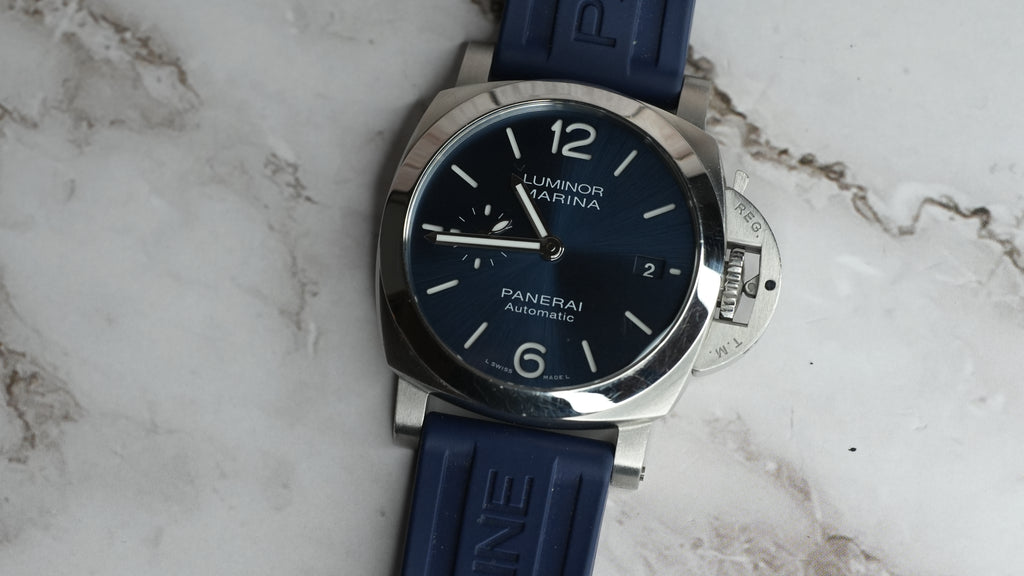 Angled front view of Panerai Luminor Marina PAM01370 showing blue dial, crown guard and surface scratches on the polished bezel.